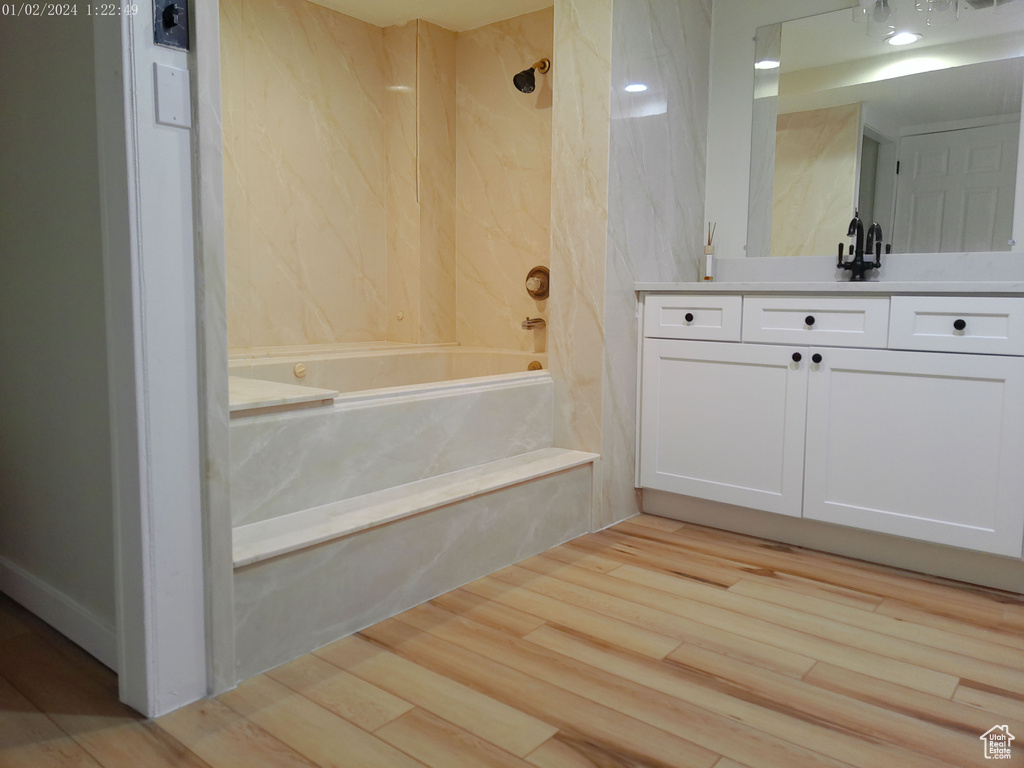 Full bathroom with vanity, a combined bath / shower with marble appearance, and wood finished floors