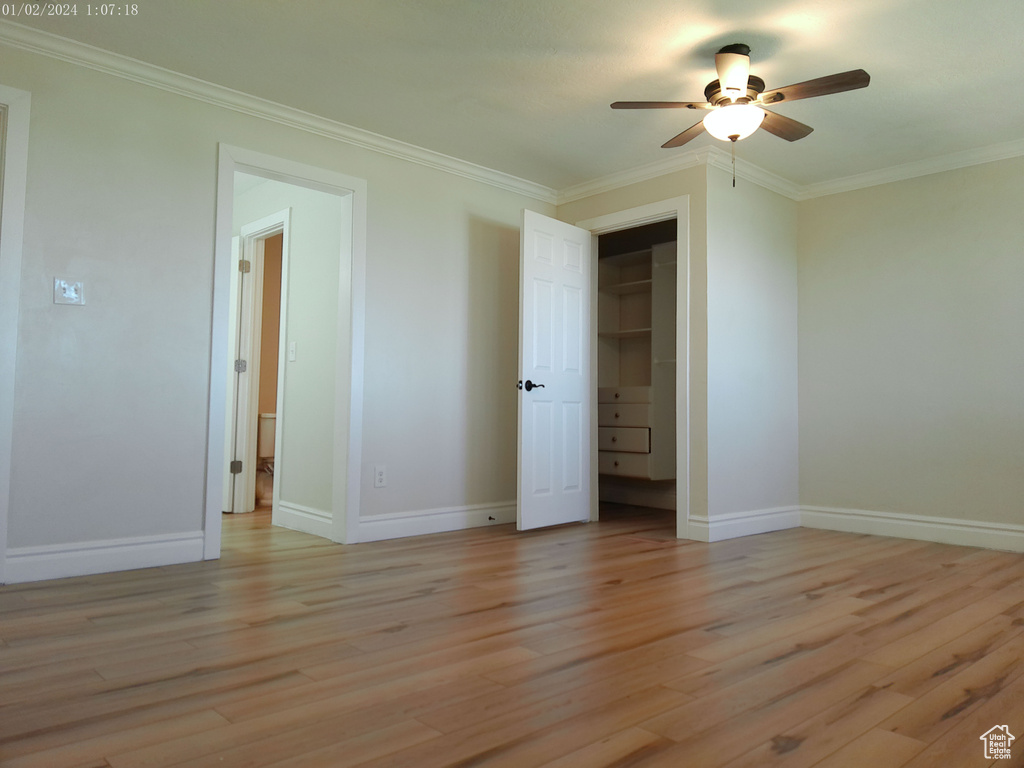 Unfurnished bedroom featuring light wood finished floors, ornamental molding, baseboards, and a ceiling fan