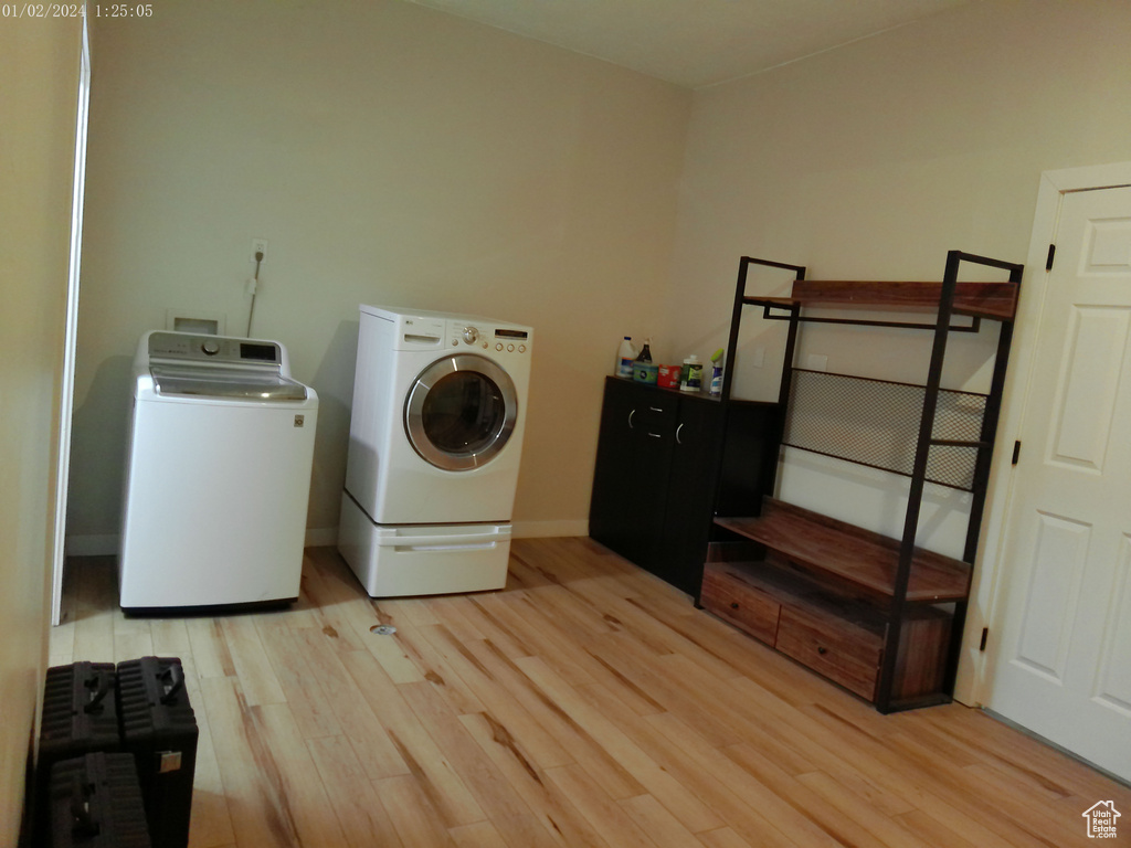 Laundry room featuring light wood-style floors, washing machine and clothes dryer, and baseboards