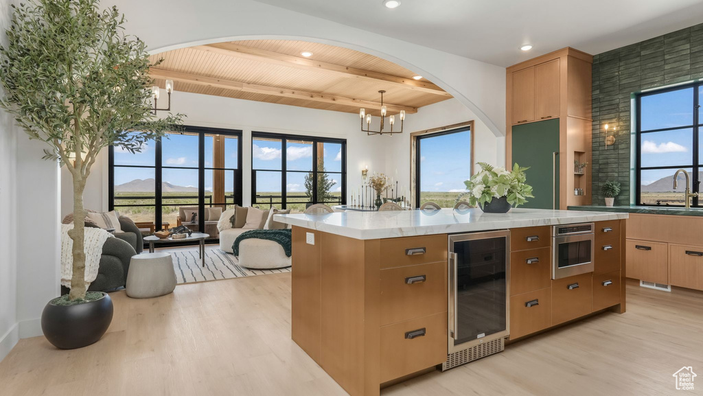 Kitchen featuring beverage cooler, light wood-type flooring, wood ceiling with exposed beams, plenty of natural light, and recessed lighting