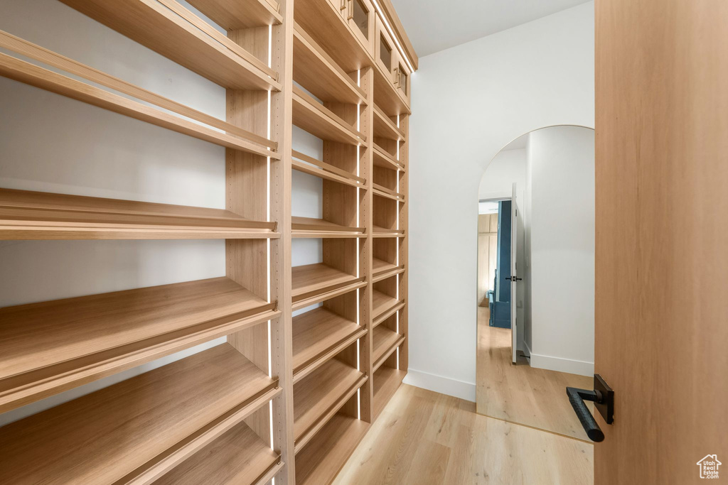Spacious closet featuring arched walkways and wood finished floors