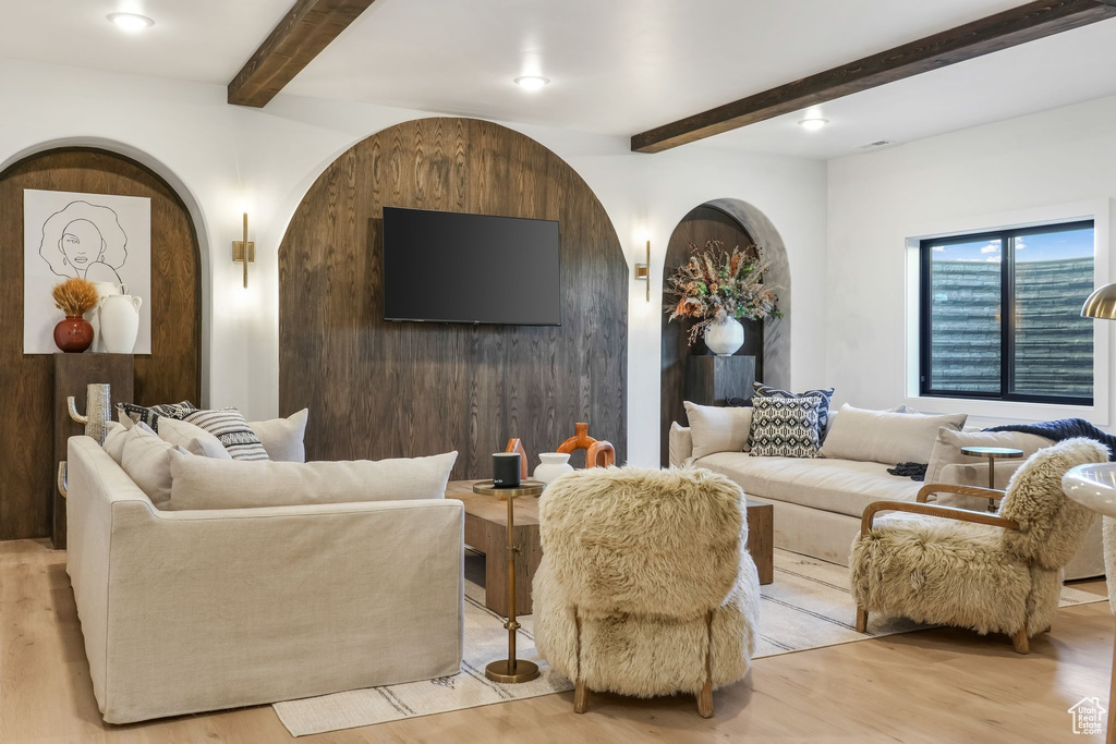 Living room featuring beam ceiling, light wood-type flooring, and arched walkways