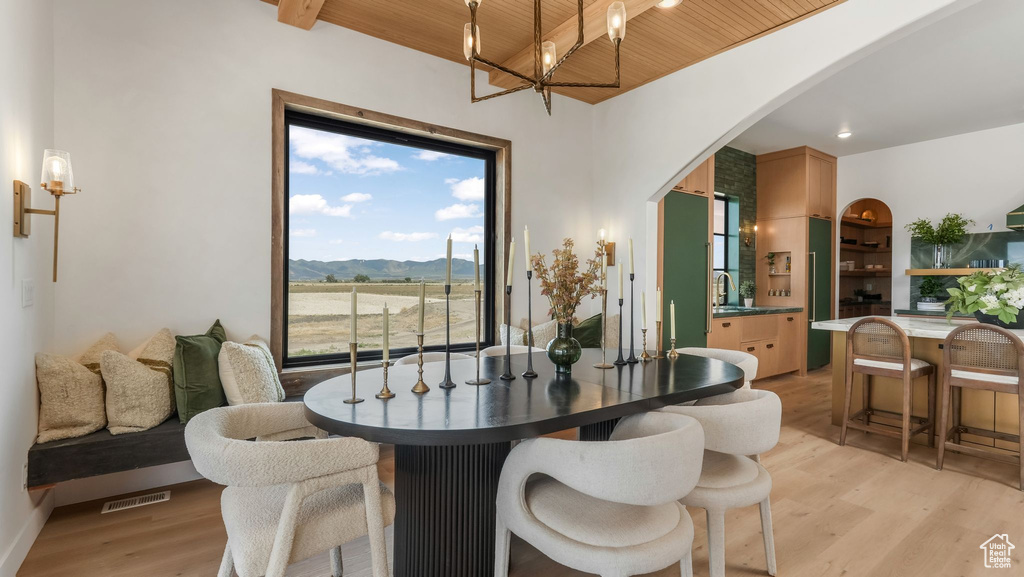 Dining space featuring wood ceiling with exposed beams, a mountain view, light wood finished floors, and arched walkways