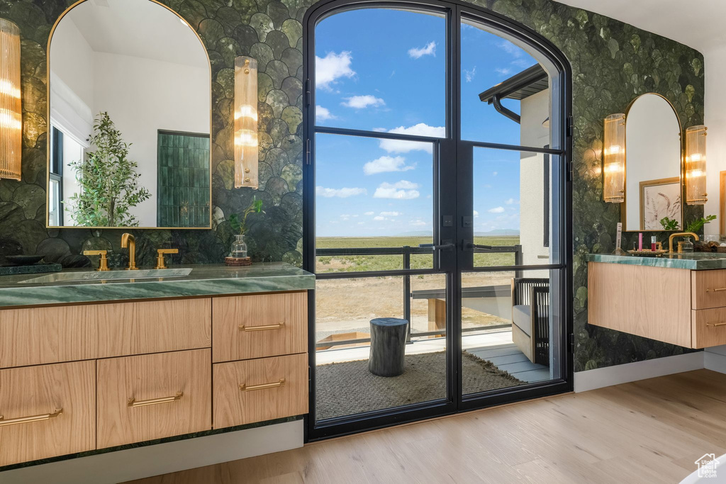 Bathroom featuring wallpapered walls, wood finished floors, vanity, decorative backsplash, and french doors