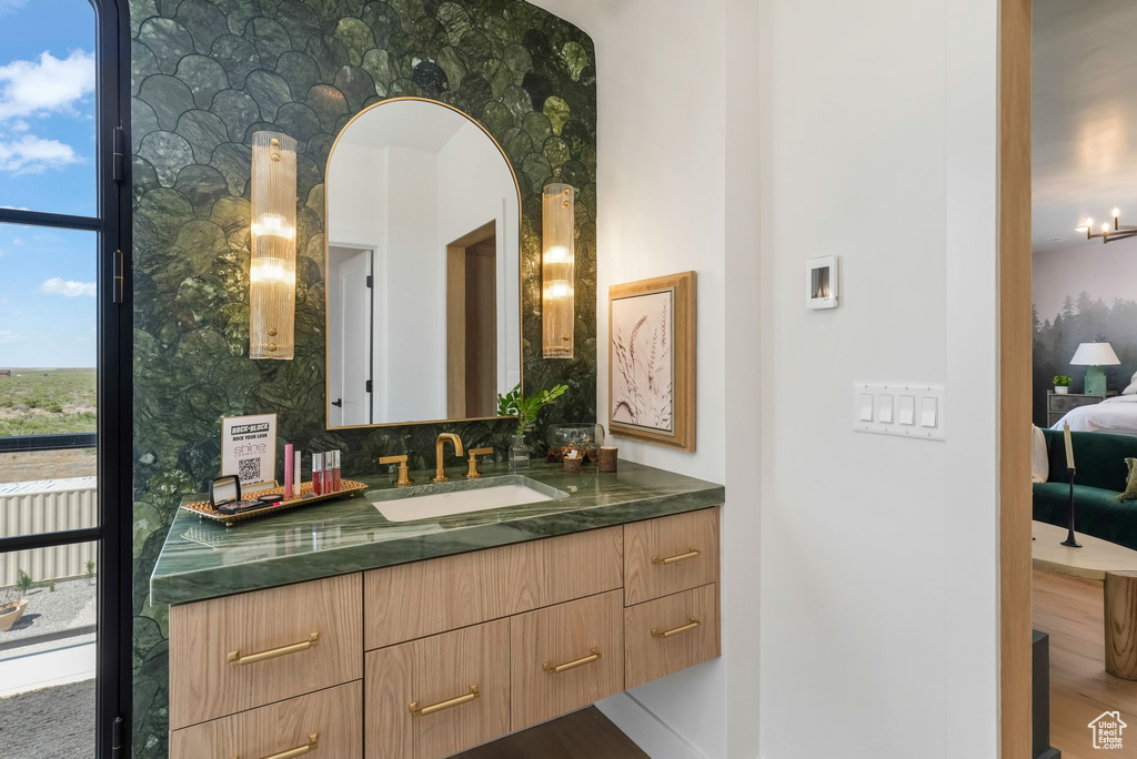 Bathroom with vanity, connected bathroom, tasteful backsplash, and wood finished floors