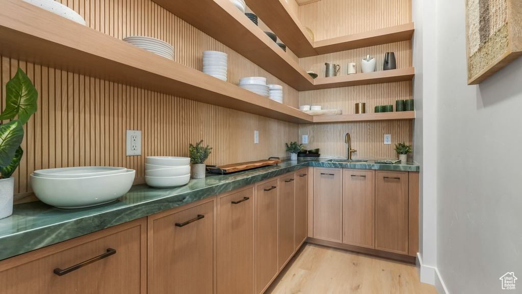 Bar featuring light wood-style floors, a sink, and baseboards