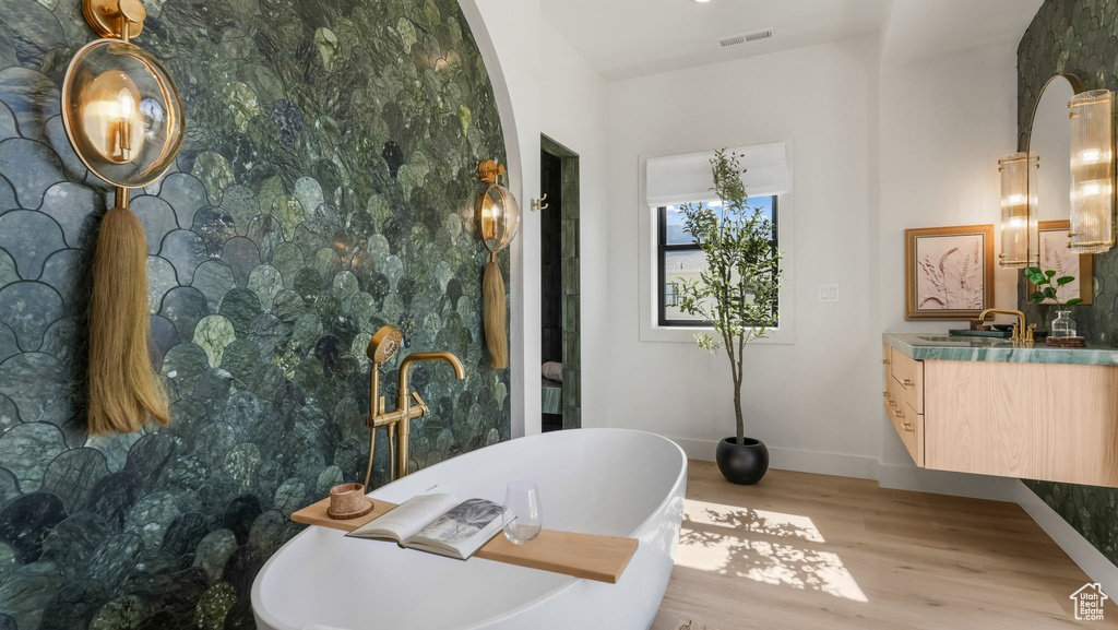 Bathroom featuring vanity, a freestanding tub, wood finished floors, and baseboards