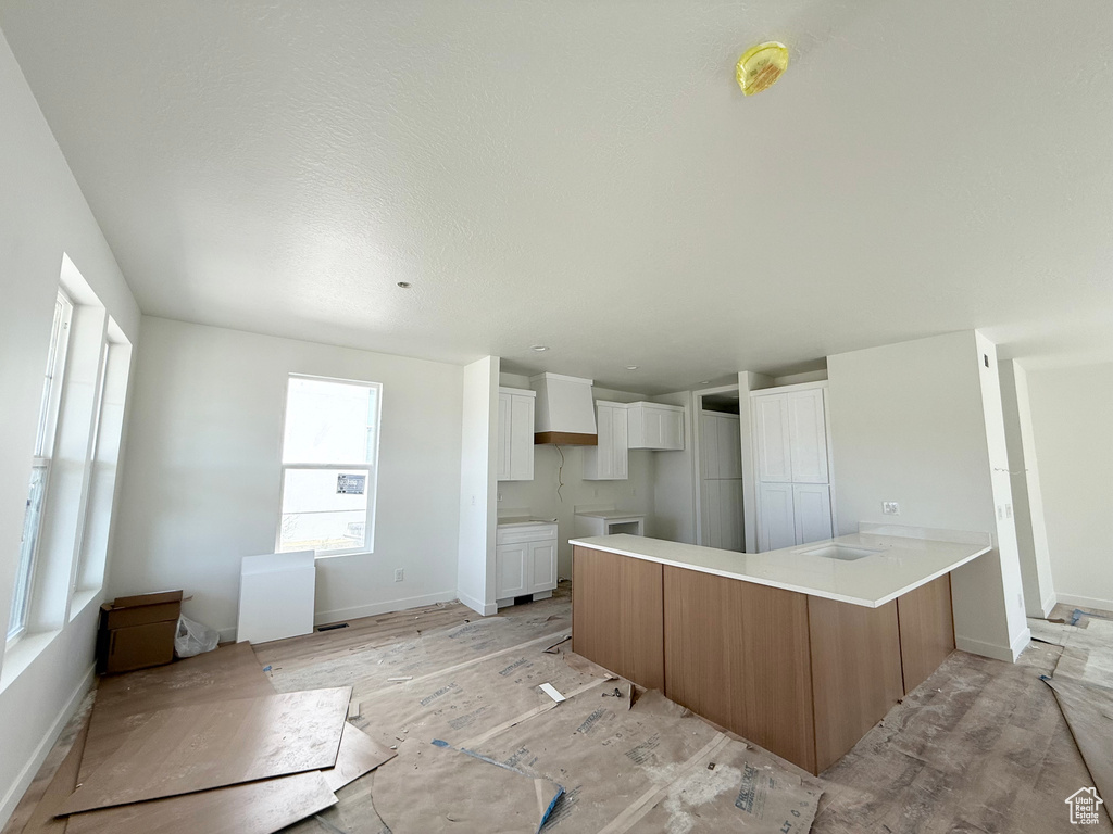 Kitchen featuring a peninsula, white cabinets, and light countertops