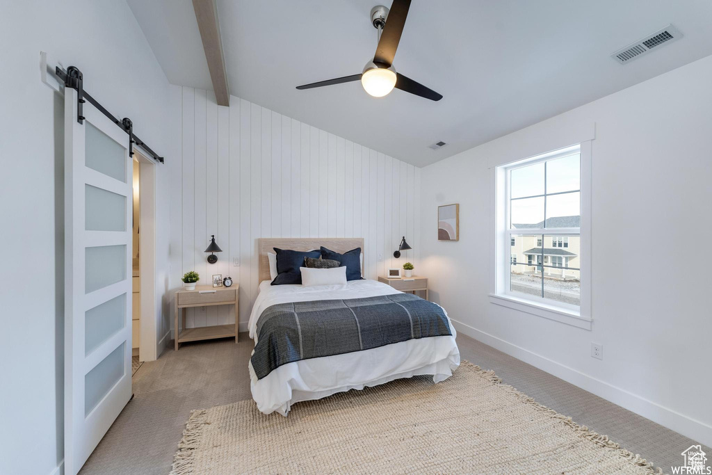 Carpeted bedroom with a barn door, a ceiling fan, baseboards, and beam ceiling