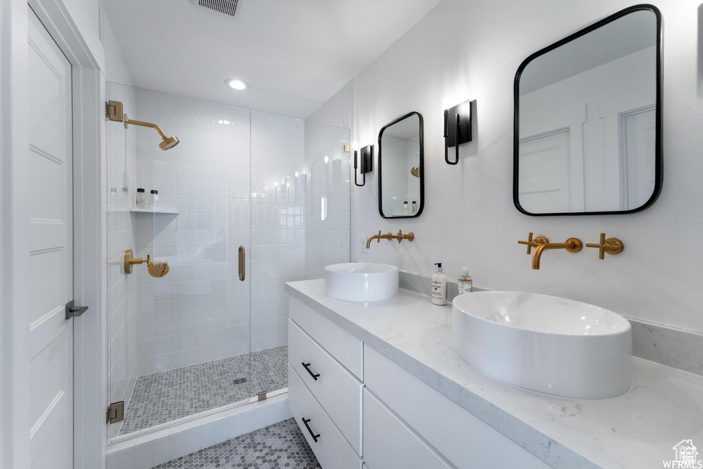 Bathroom featuring a shower stall, double vanity, and recessed lighting