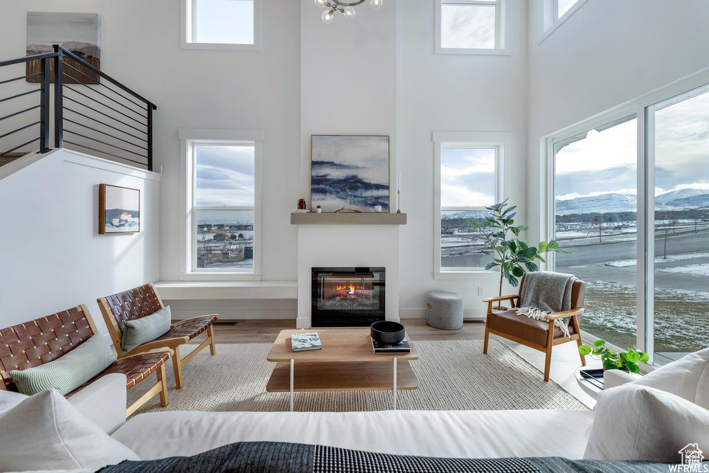 Living area featuring a towering ceiling, wood finished floors, a glass covered fireplace, stairs, and baseboards