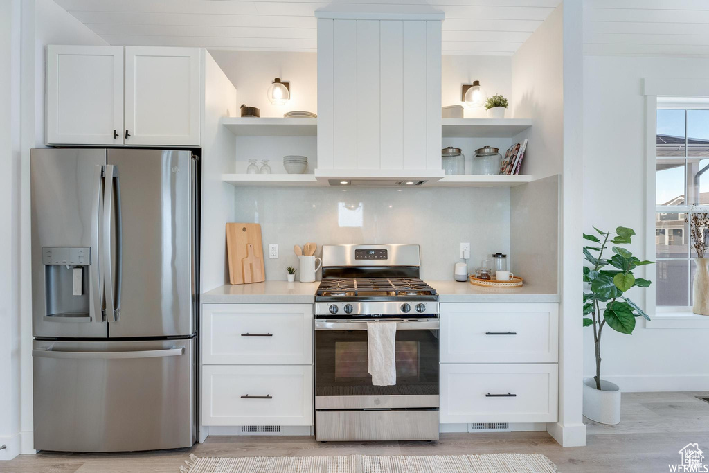 Kitchen with stainless steel appliances, open shelves, and white cabinets