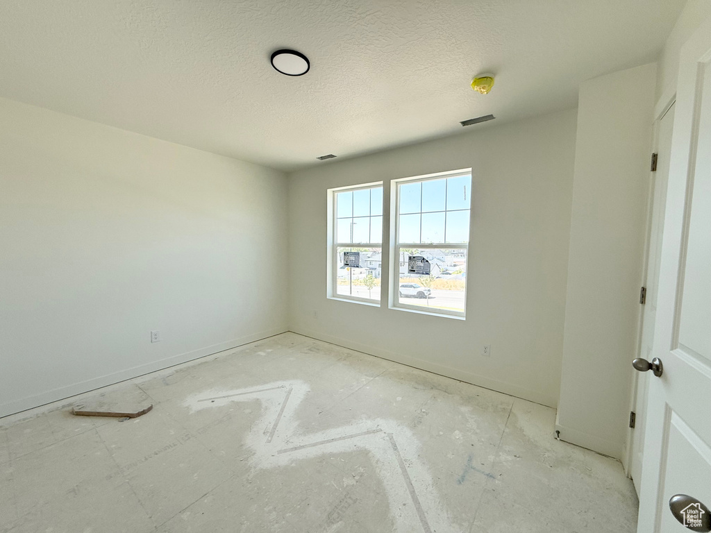 Unfurnished room featuring a textured ceiling and baseboards