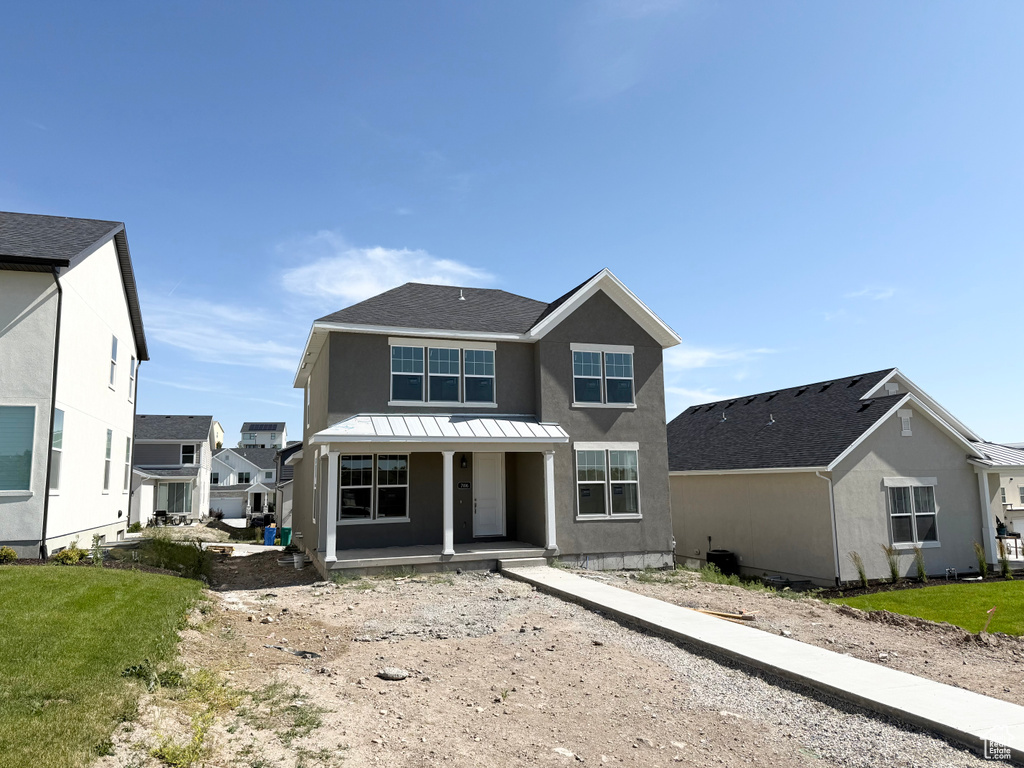 View of front of house featuring covered porch, stucco siding, a standing seam roof, a metal roof, and a shingled roof