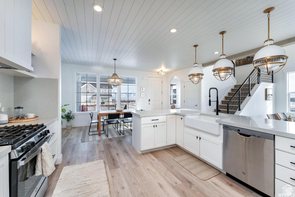 Kitchen with stainless steel dishwasher, a sink, gas stove, a chandelier, and wooden ceiling