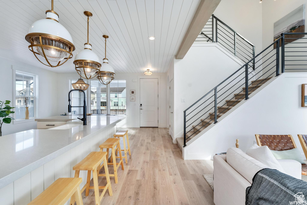 Kitchen with light wood-style flooring, a breakfast bar, plenty of natural light, decorative light fixtures, and wood ceiling
