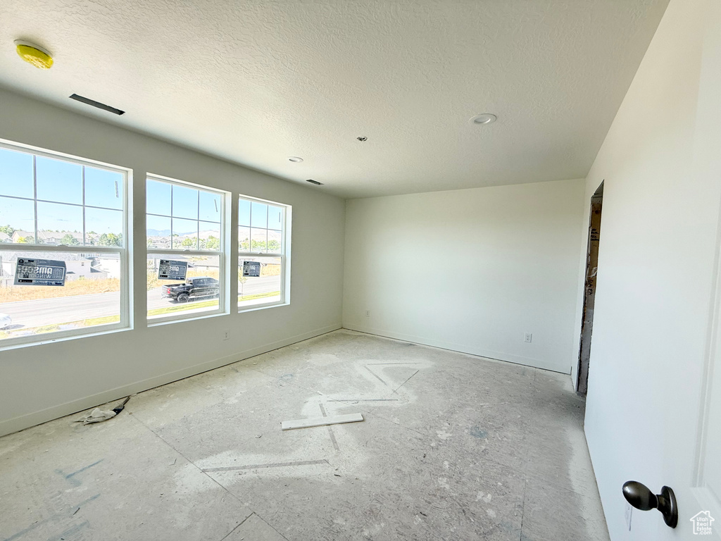 Unfurnished room with a textured ceiling and a smoke detector
