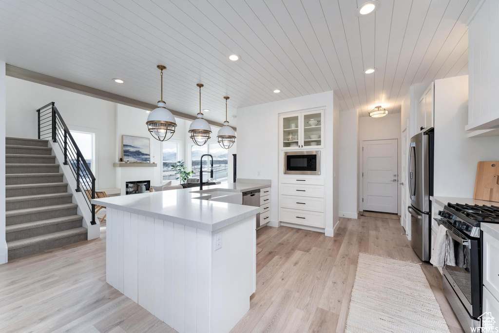 Kitchen with appliances with stainless steel finishes, white cabinetry, light wood-style floors, light countertops, and recessed lighting