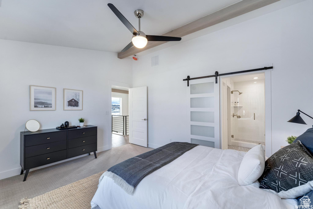 Bedroom with a barn door, light carpet, ensuite bath, and ceiling fan