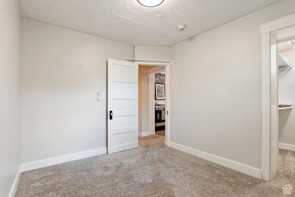 Unfurnished bedroom with carpet floors, baseboards, and a textured ceiling