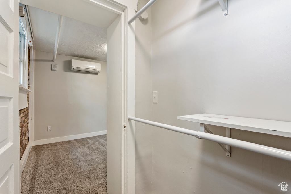 Spacious closet featuring a wall unit AC and carpet