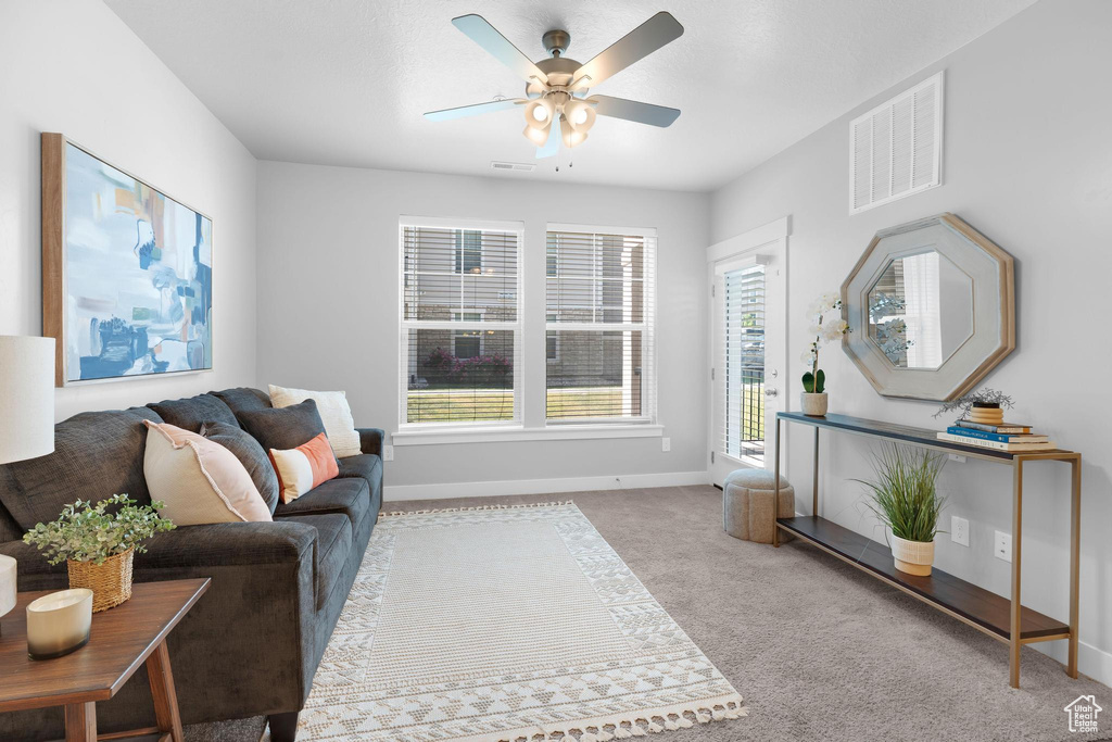 Living area with a ceiling fan, baseboards, and carpet floors
