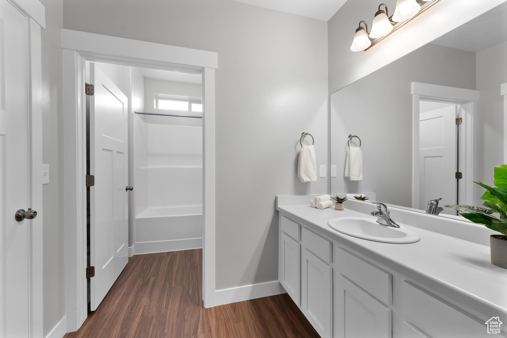Full bathroom with vanity, wood finished floors, baseboards, and shower / bath combination