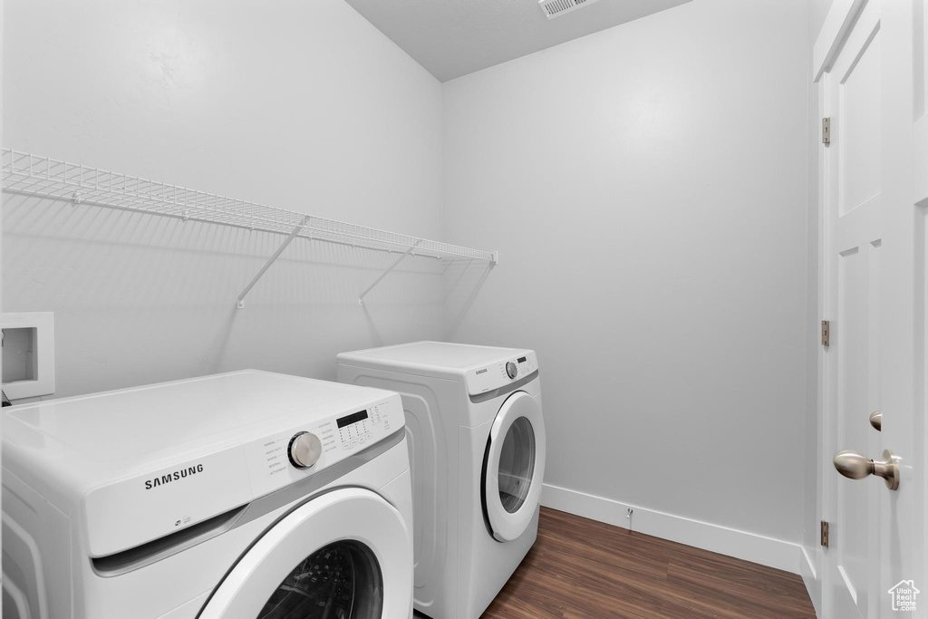 Washroom with washer and clothes dryer, baseboards, and dark wood finished floors