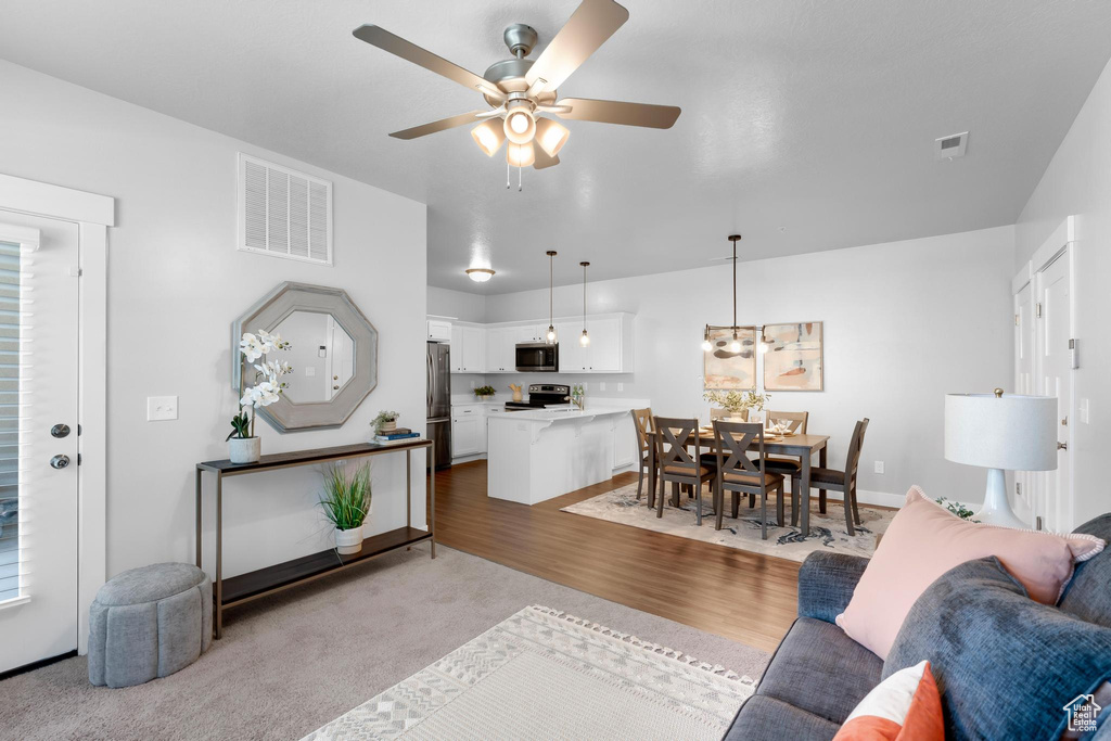 Living room featuring a ceiling fan, carpet flooring, wood finished floors, and baseboards