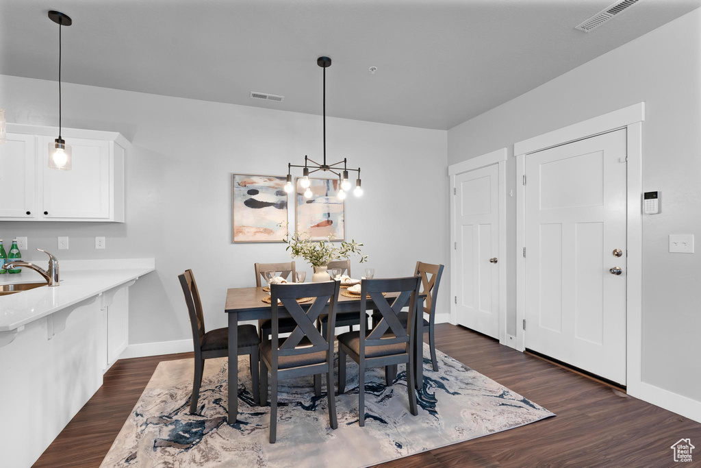 Dining area featuring baseboards, dark wood-style flooring, and a chandelier