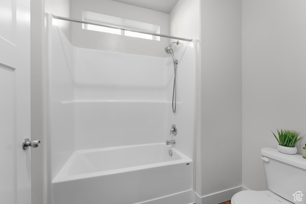 Full bathroom with toilet, shower / washtub combination, and baseboards