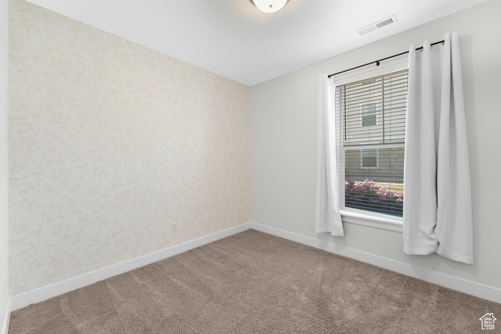 Carpeted empty room with wallpapered walls and baseboards