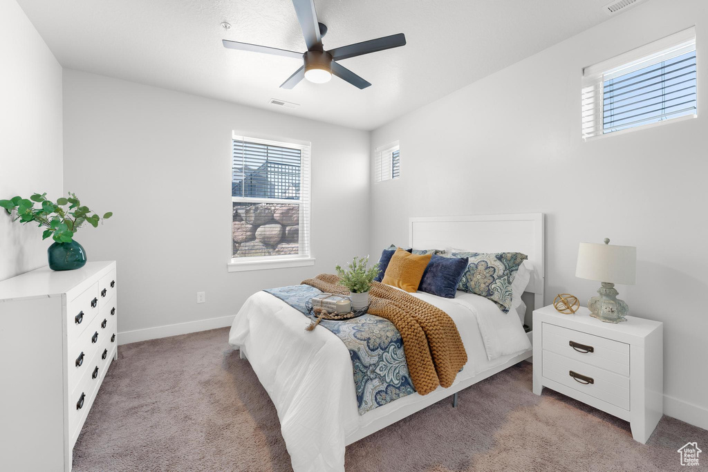 Bedroom featuring multiple windows, light colored carpet, baseboards, and a ceiling fan