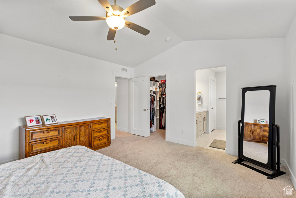 Bedroom with a spacious closet, vaulted ceiling, light carpet, a closet, and ensuite bathroom