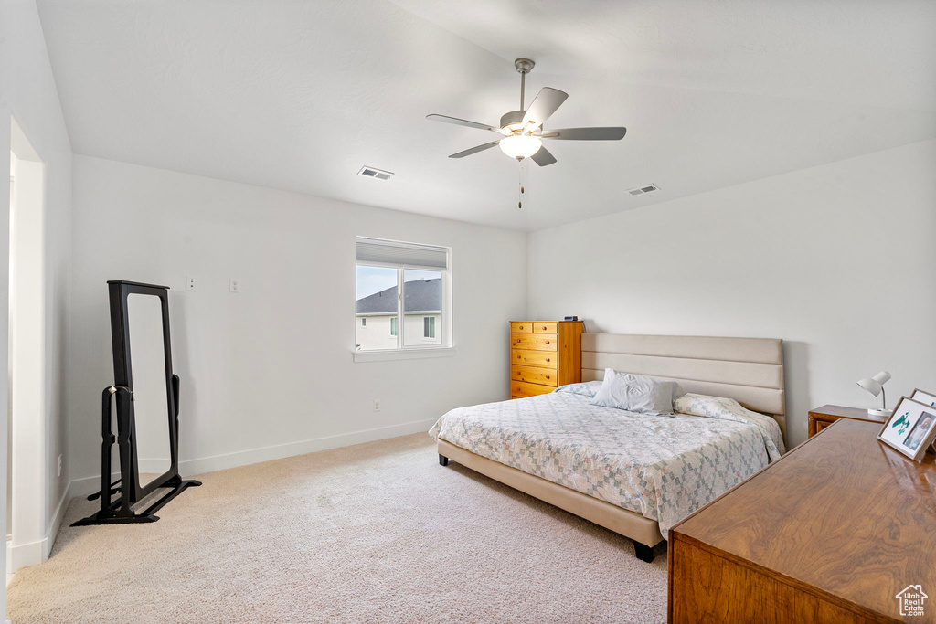 Bedroom with light colored carpet, baseboards, and ceiling fan