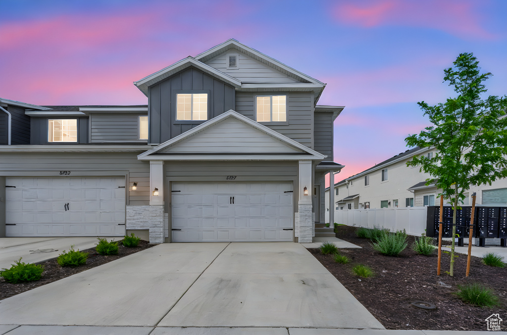 Traditional home featuring board and batten siding, concrete driveway, a garage, and stone siding