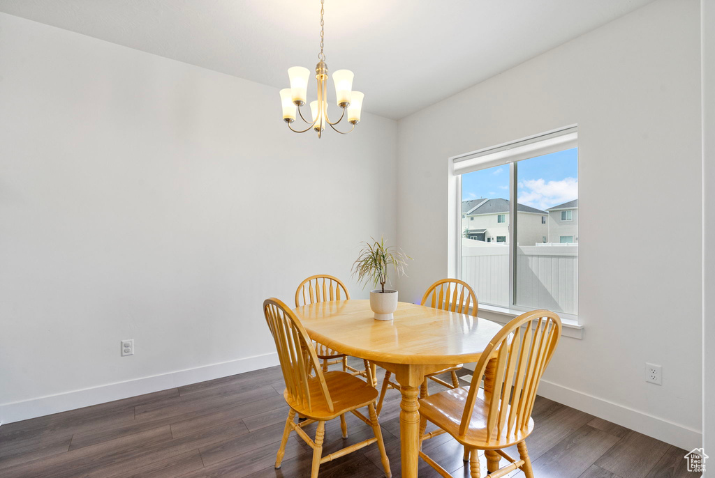 Dining area featuring a chandelier, baseboards, and dark wood-style floors