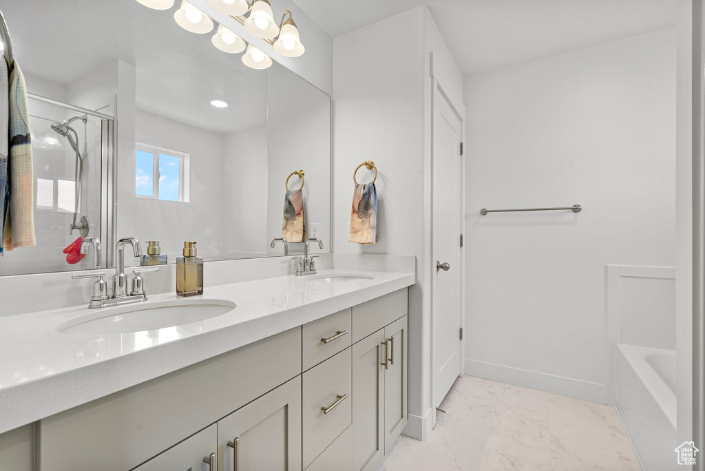 Full bathroom featuring a shower with shower door, marble finish floors, double vanity, a bathtub, and baseboards