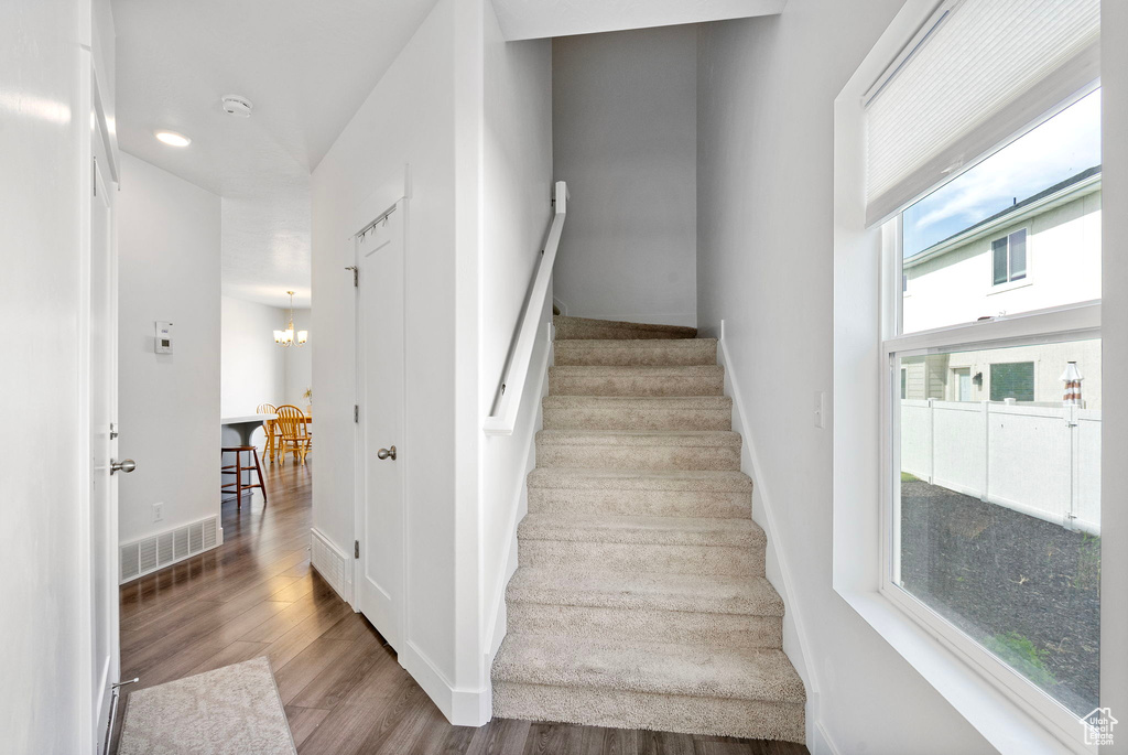 Stairway with wood finished floors, baseboards, and a chandelier