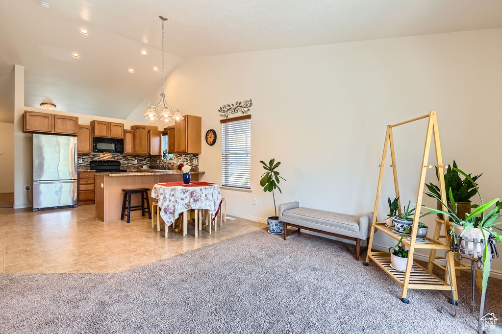 Dining area featuring a chandelier, baseboards, high vaulted ceiling, light tile patterned floors, and light carpet