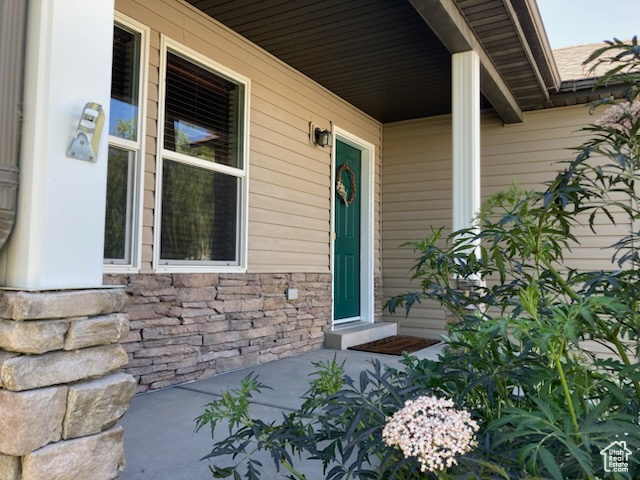 Doorway to property with covered porch and stone siding