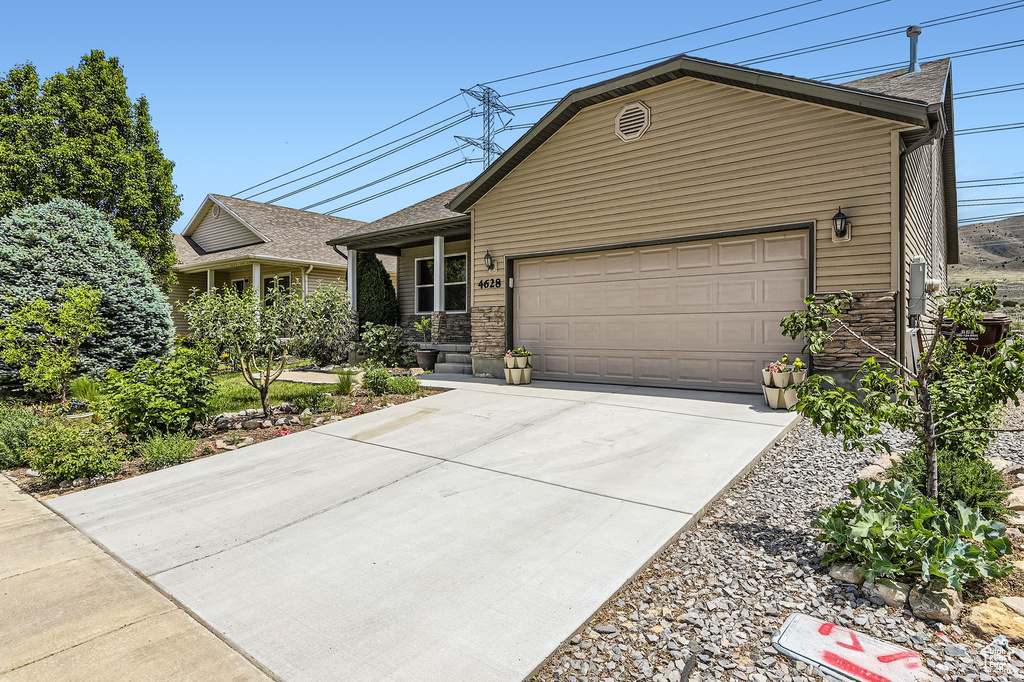 Ranch-style house featuring concrete driveway, a garage, and stone siding