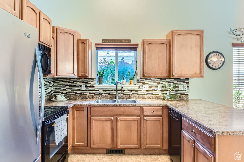 Kitchen featuring black appliances, a sink, a peninsula, backsplash, and healthy amount of natural light