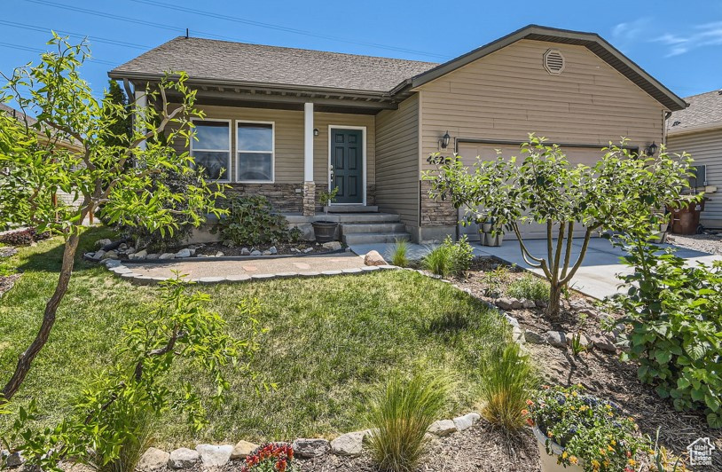 Ranch-style home with an attached garage, a front lawn, roof with shingles, and covered porch