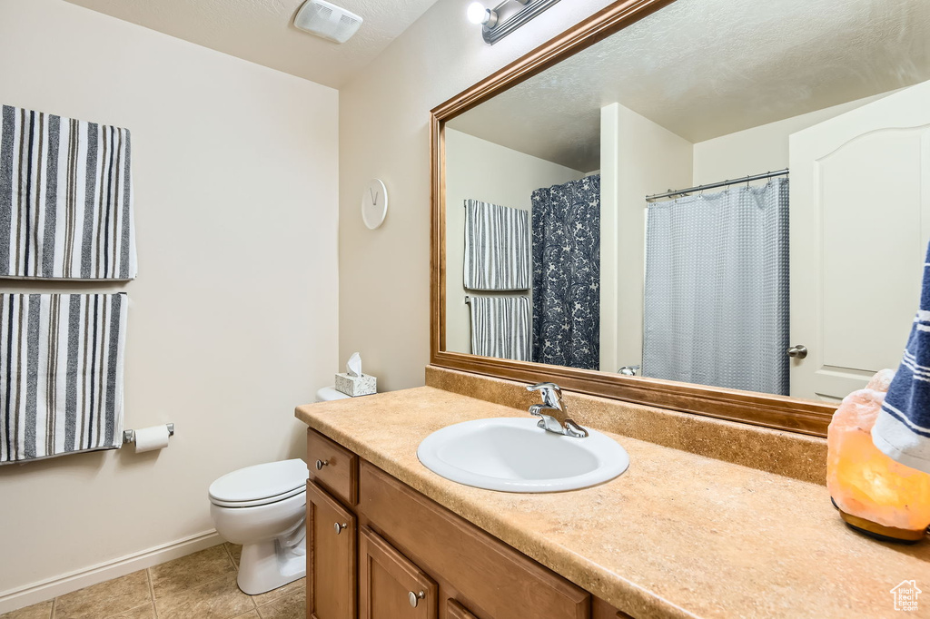 Full bathroom featuring vanity, toilet, tile patterned flooring, and baseboards