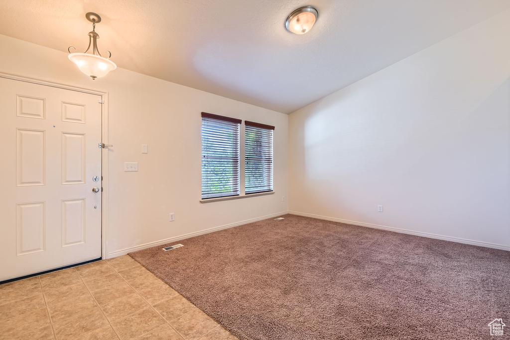 Foyer entrance with light colored carpet and baseboards
