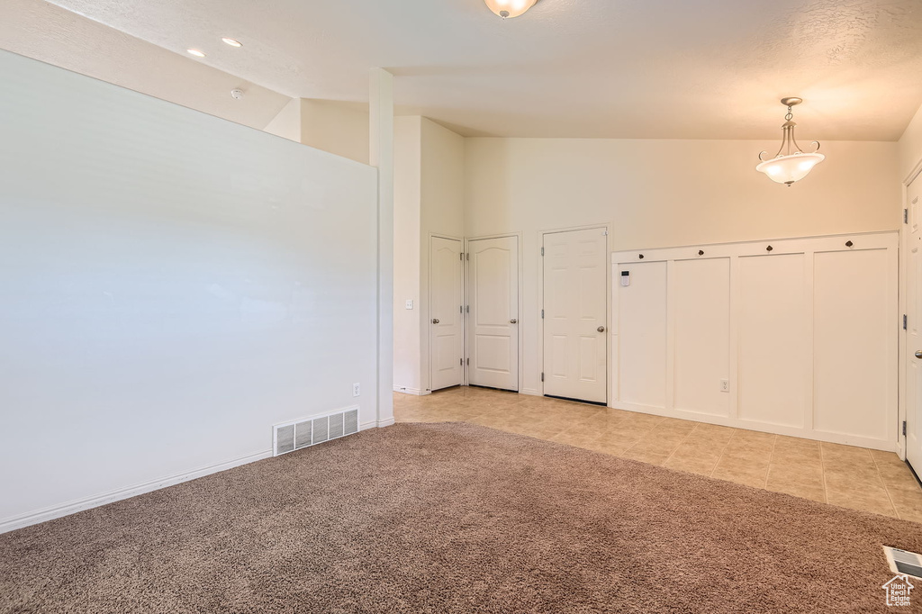 Spare room with light carpet, light tile patterned flooring, lofted ceiling, and baseboards