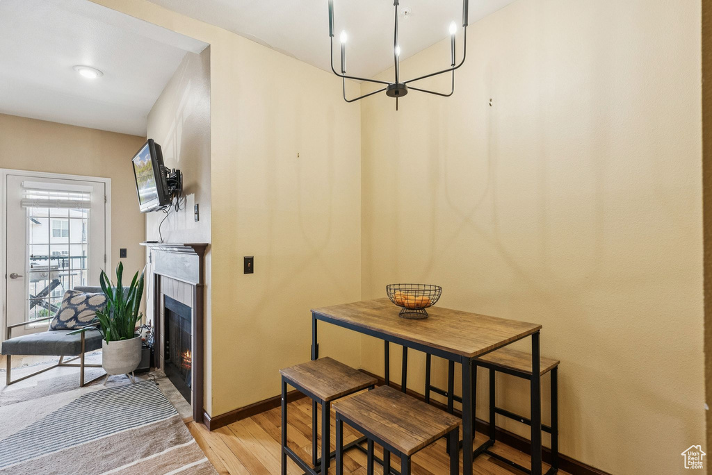 Dining room featuring light wood-type flooring, a lit fireplace, baseboards, and a chandelier