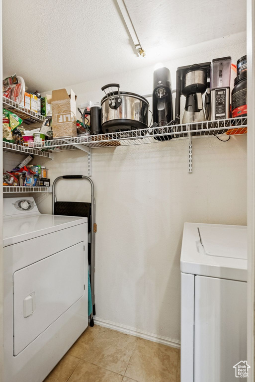 Washroom with separate washer and dryer, light tile patterned flooring, and baseboards