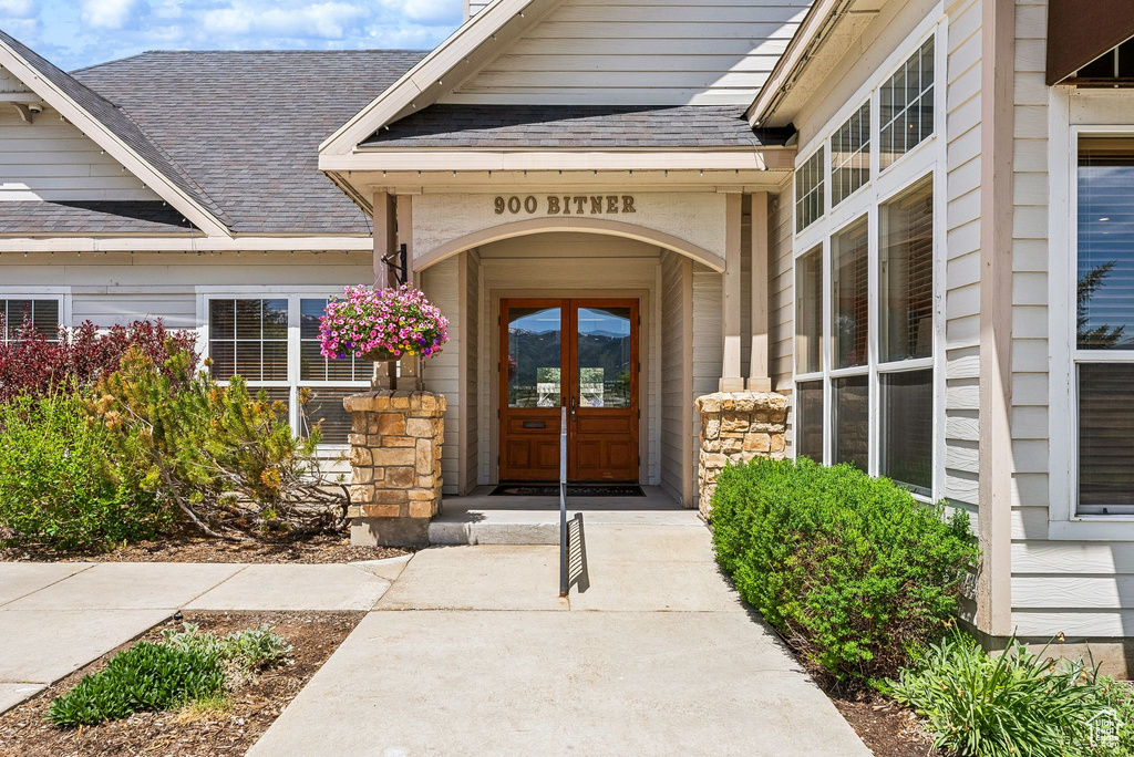 Doorway to property featuring a shingled roof
